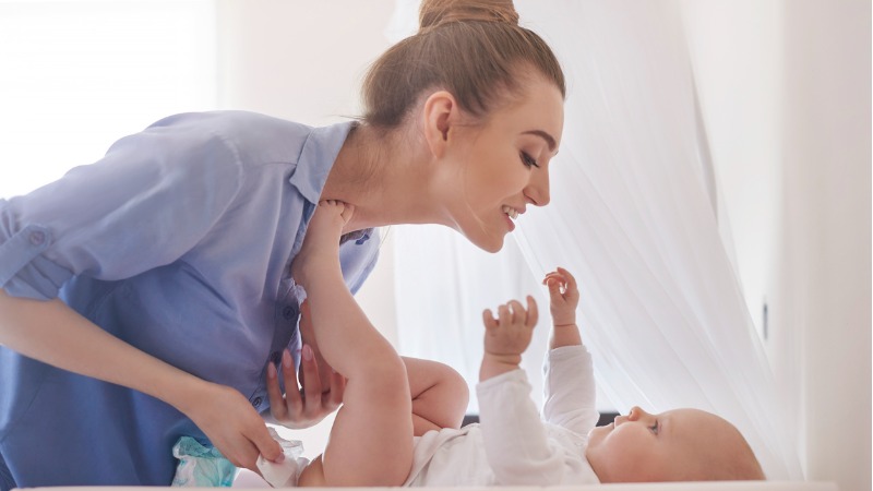 Femme penchée vers le bébé qu'elle change